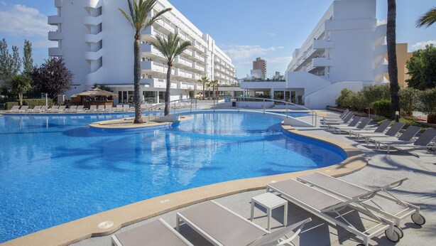 A swimming pool with lounge chairs and palm trees, surrounded by white buildings. - HM Martinique Aparthotel (Calvia)