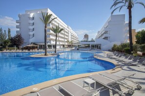 A swimming pool with lounge chairs and palm trees, surrounded by white buildings. - HM Martinique Aparthotel (Calvia)