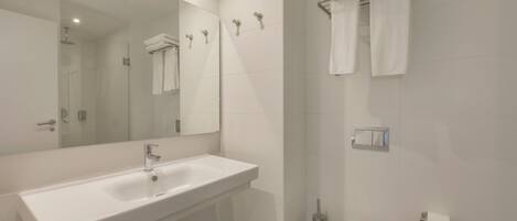 Un baño moderno con un lavabo blanco, un inodoro, una ducha y un perchero para toallas.