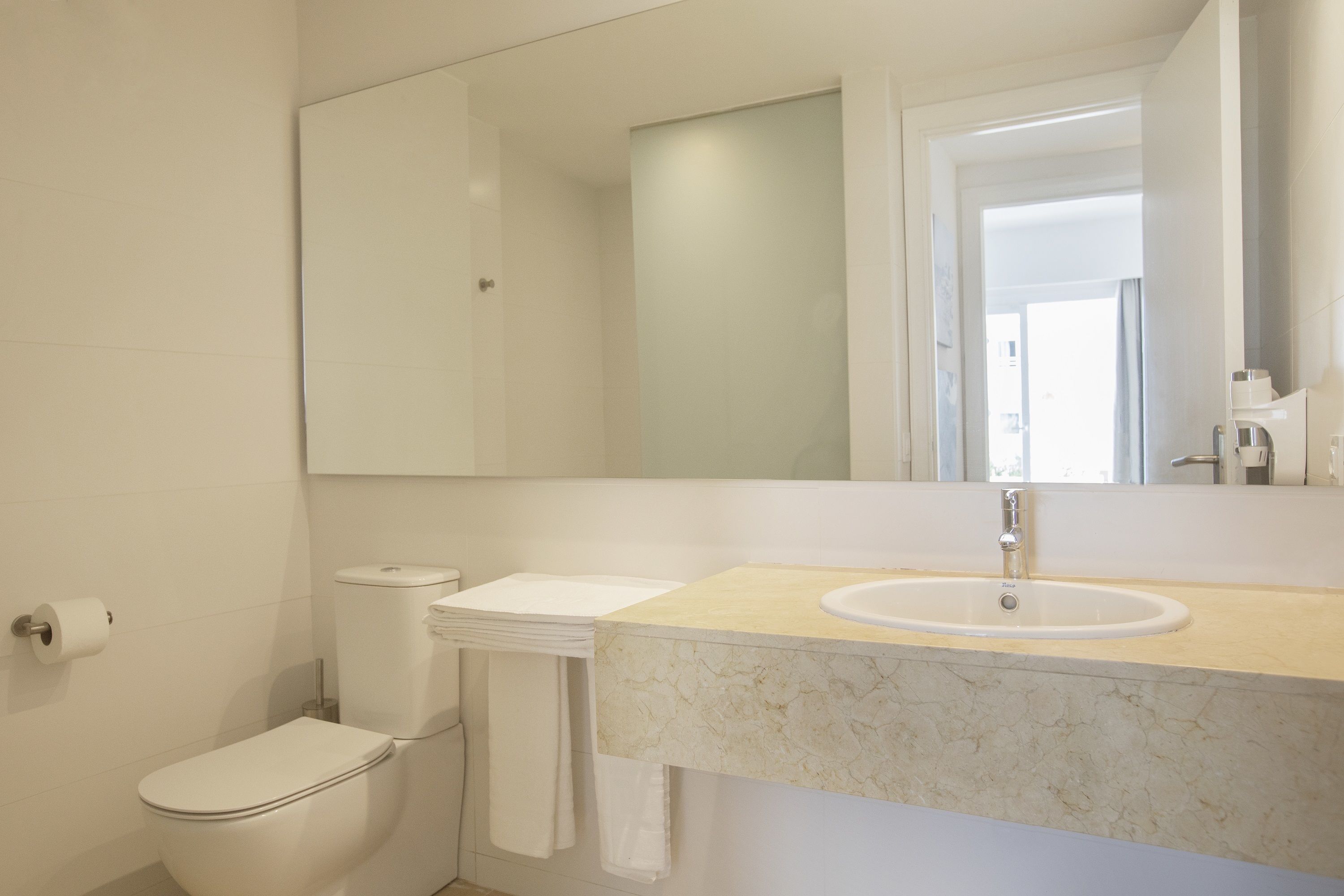 A modern bathroom with a toilet, sink, and mirror.