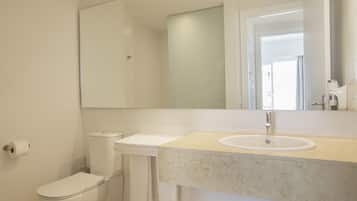 Un baño moderno con inodoro, lavamanos y espejo.