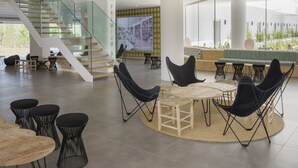 A spacious lobby with a modern staircase, comfortable seating areas, and a large digital display. - HM Martinique Aparthotel (Calvia)