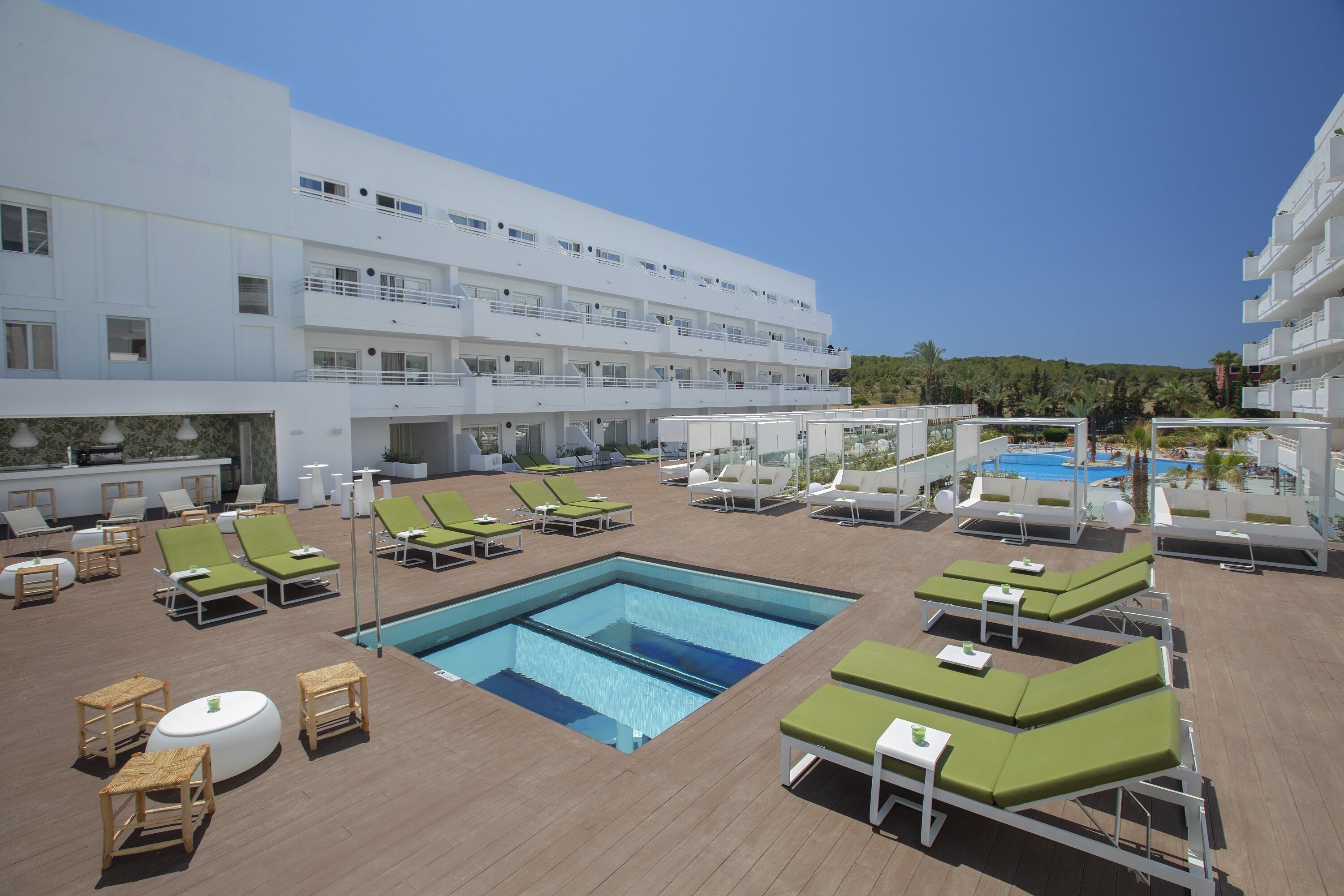Zona de piscina en la azotea con varios sillones de tomar el sol y una piscina central.