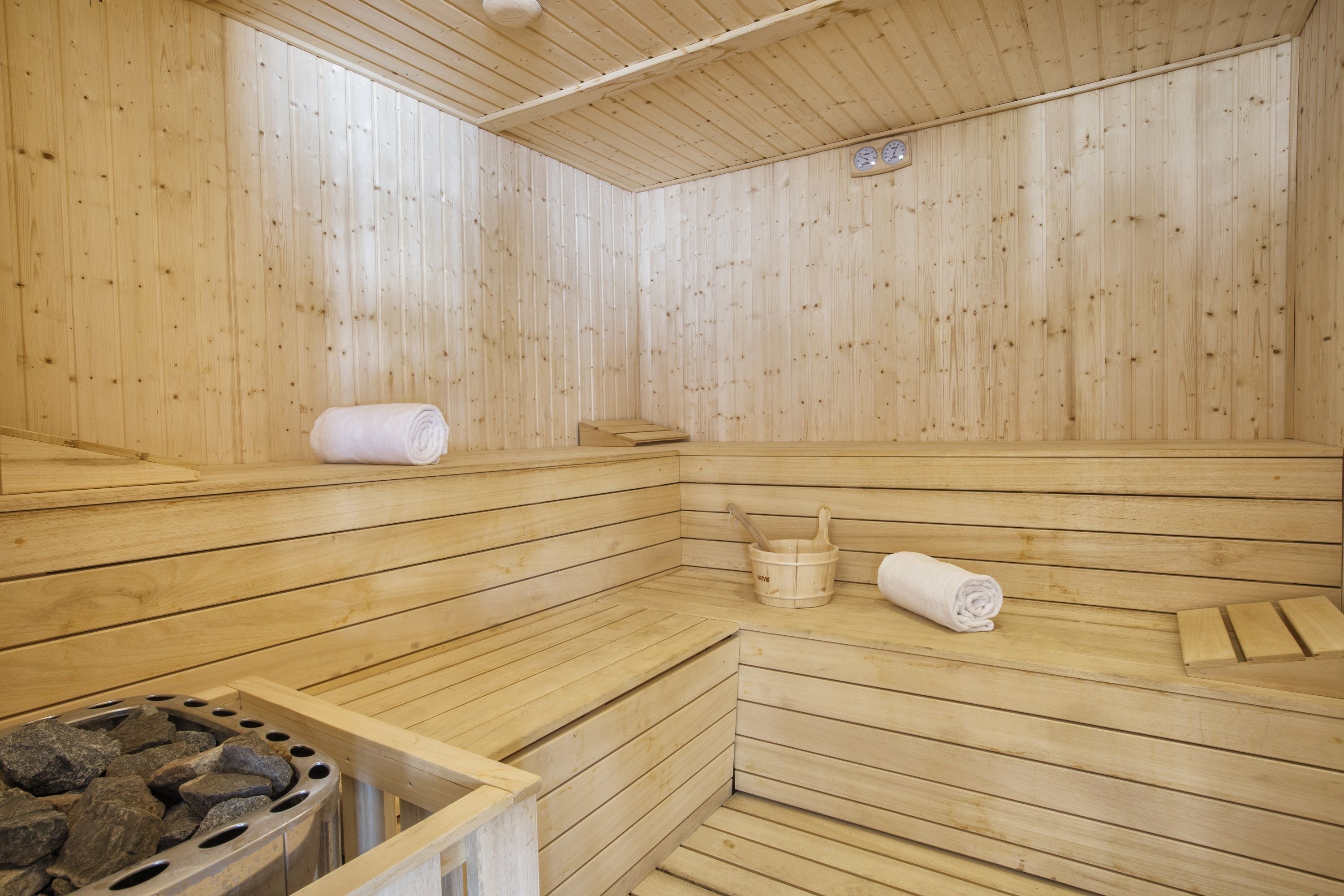 Una sauna de madera con bancos, un balde y un calentador de piedra.