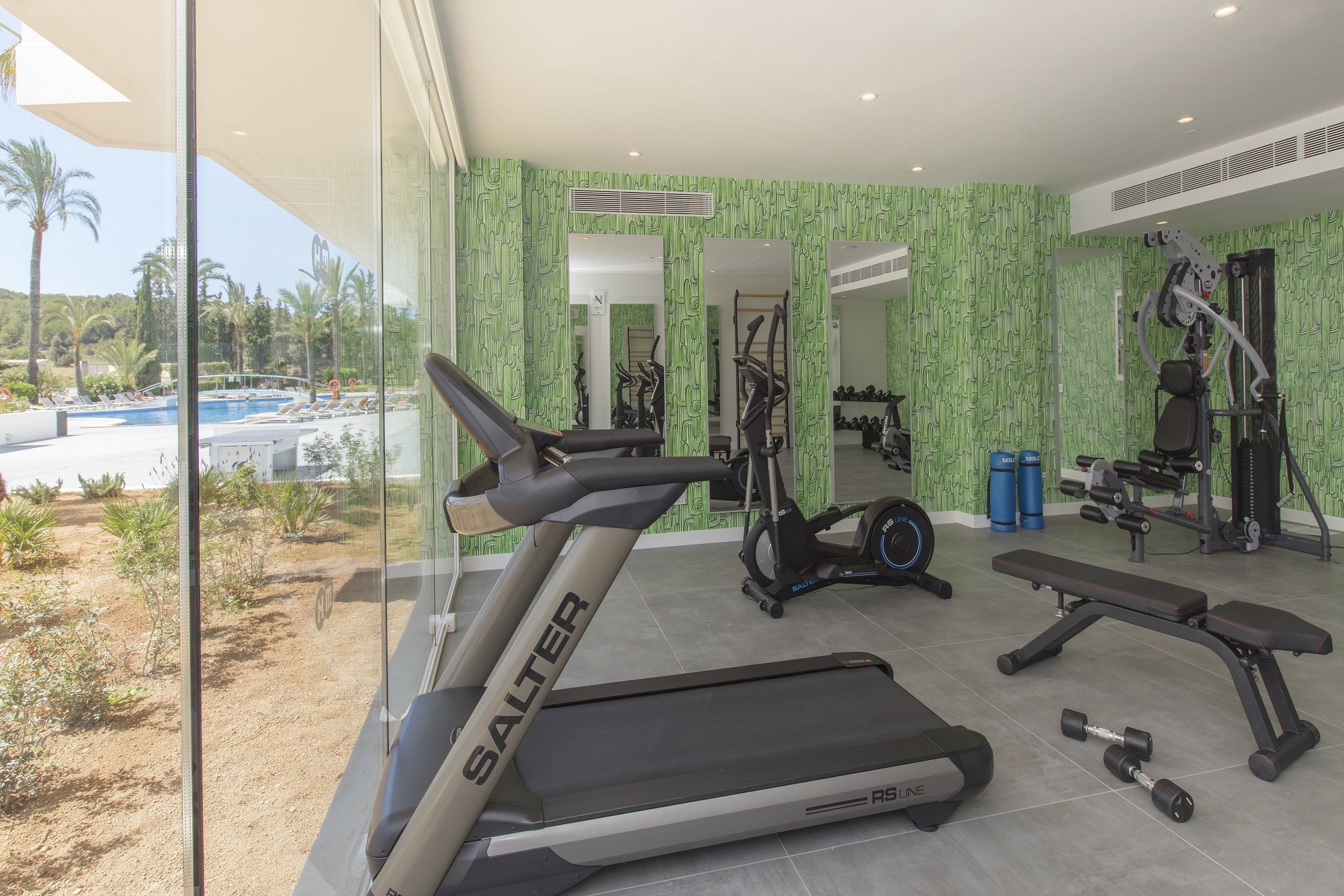 A gym with a treadmill, bench, and dumbbells.