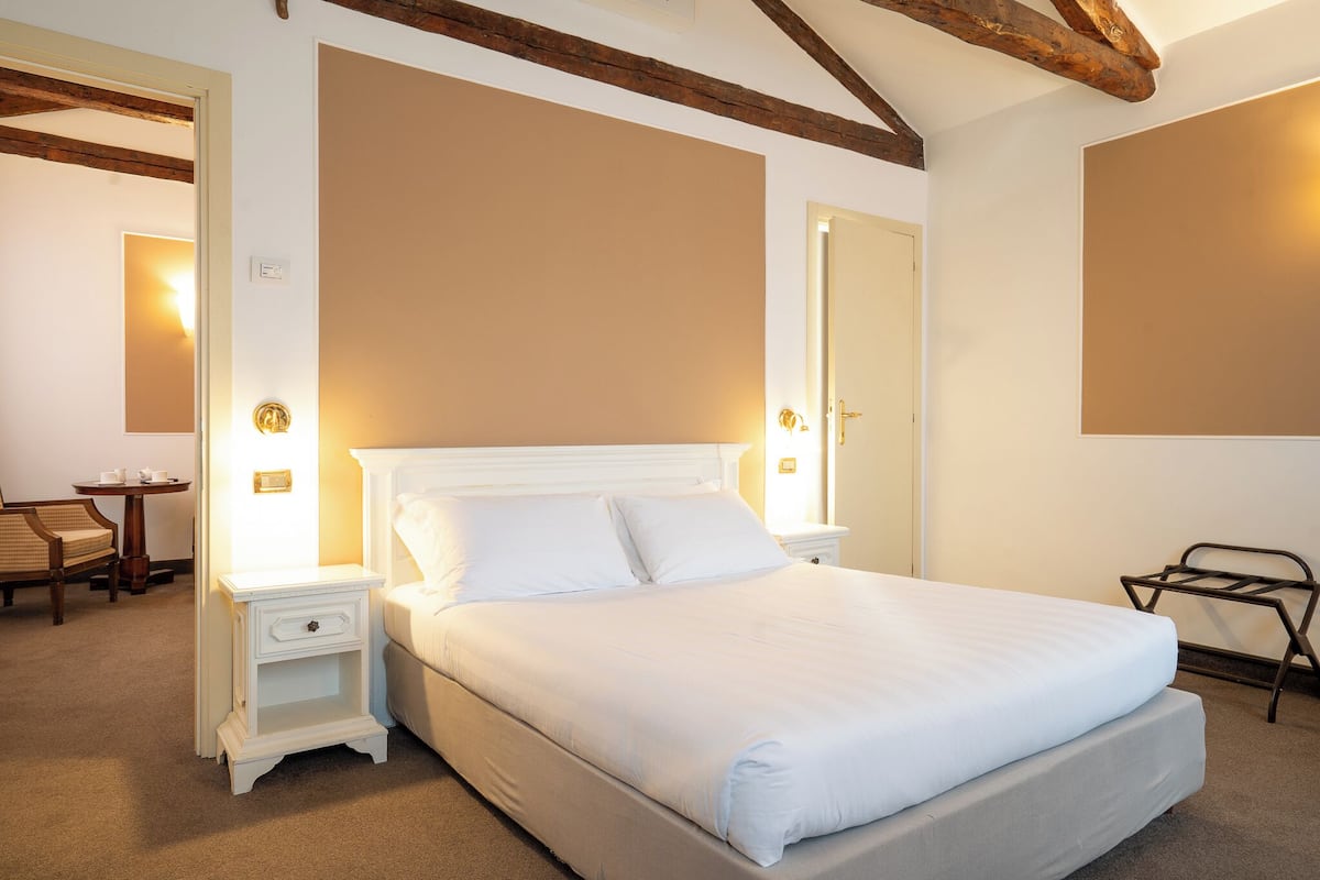 Une chambre bien rangée, avec un grand lit, des tables de chevet, une chaise et une petite table.