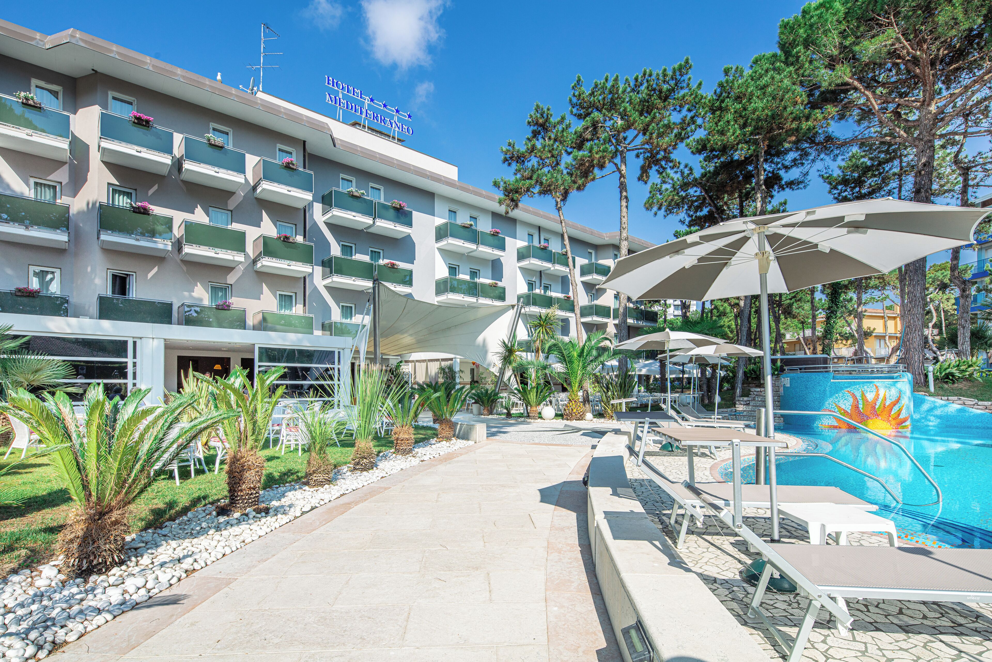 Et hotel med flere balkoner, swimmingpool og udendørs siddeområder.