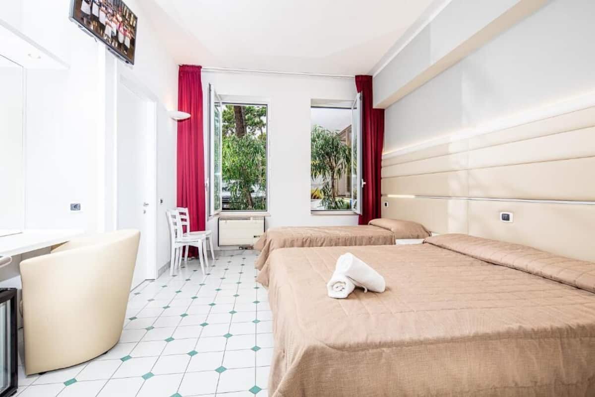 Habitación de hotel con dos camas, un escritorio y una silla.