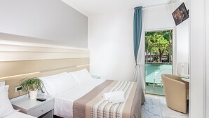 Una habitación de hotel con cama, mesita de noche y vistas a un balcón.