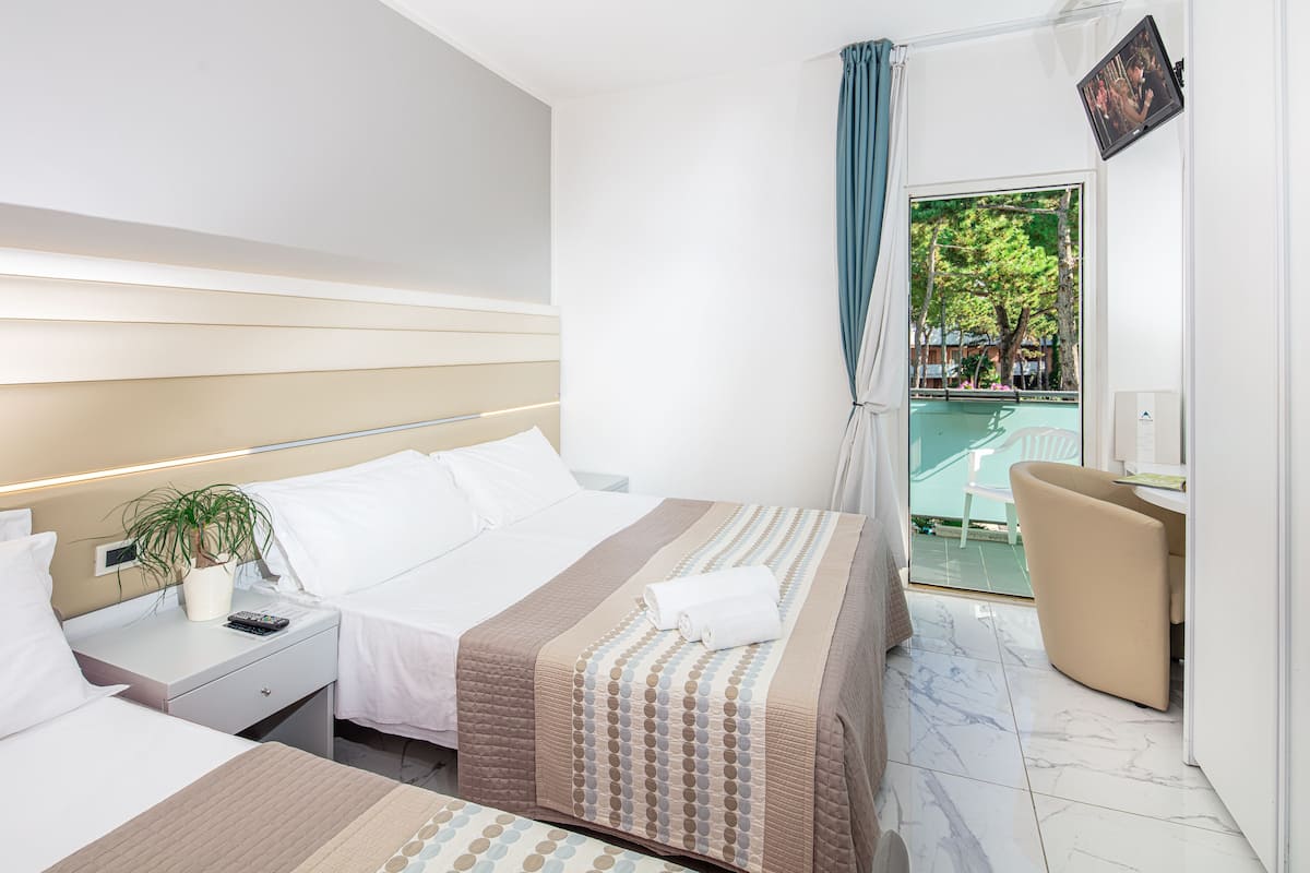 Una habitación de hotel con cama, mesita de noche y vistas a un balcón.