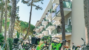 Una fila de bicicletas estacionadas frente a un edificio con balcones, rodeado de árboles.
