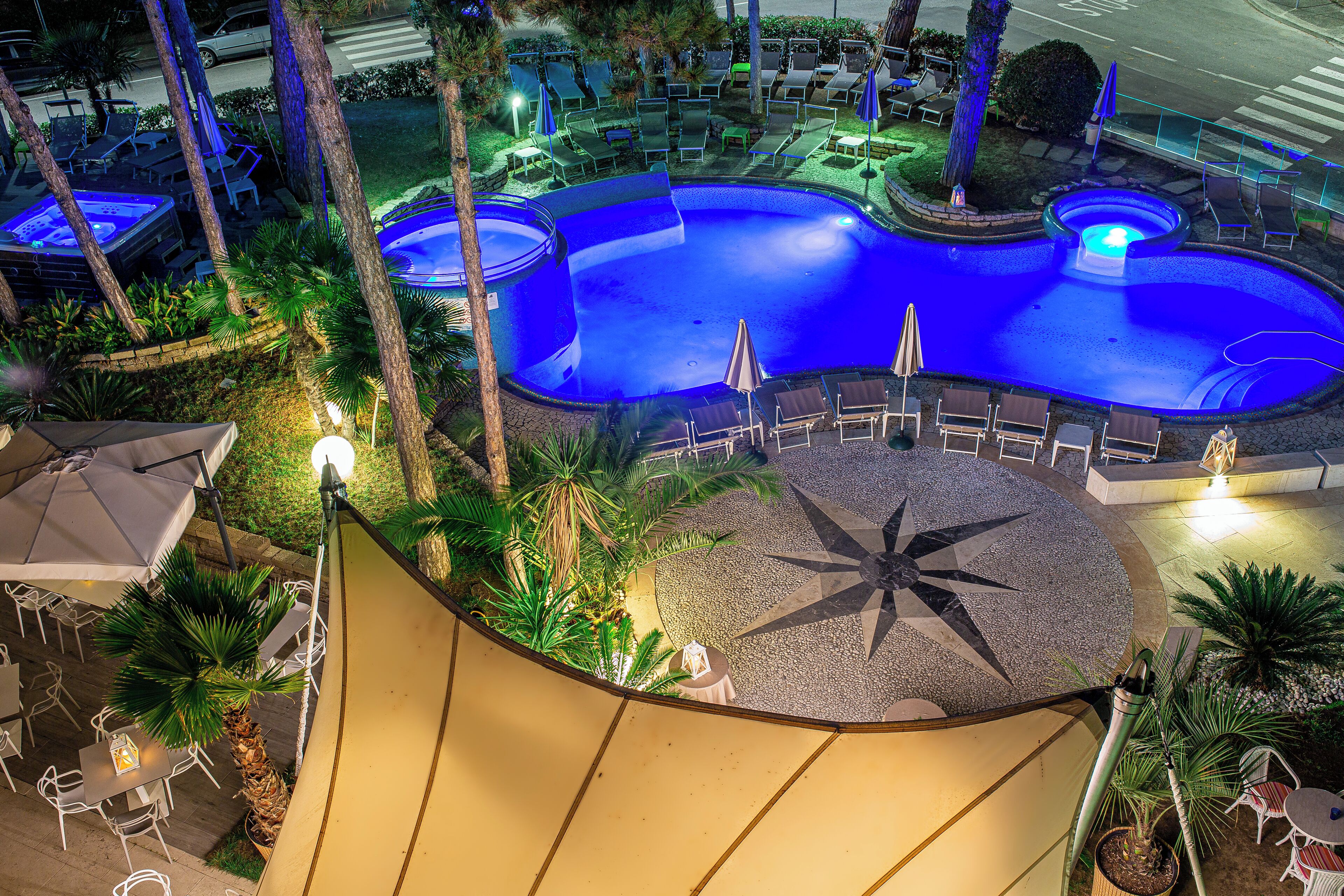 Un espace piscine aménagé sur le toit, avec des chaises longues, des parasols et un luminaire en forme d’étoile.