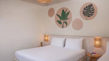 A hotel room with a bed, bedside lamps, and wall decor.