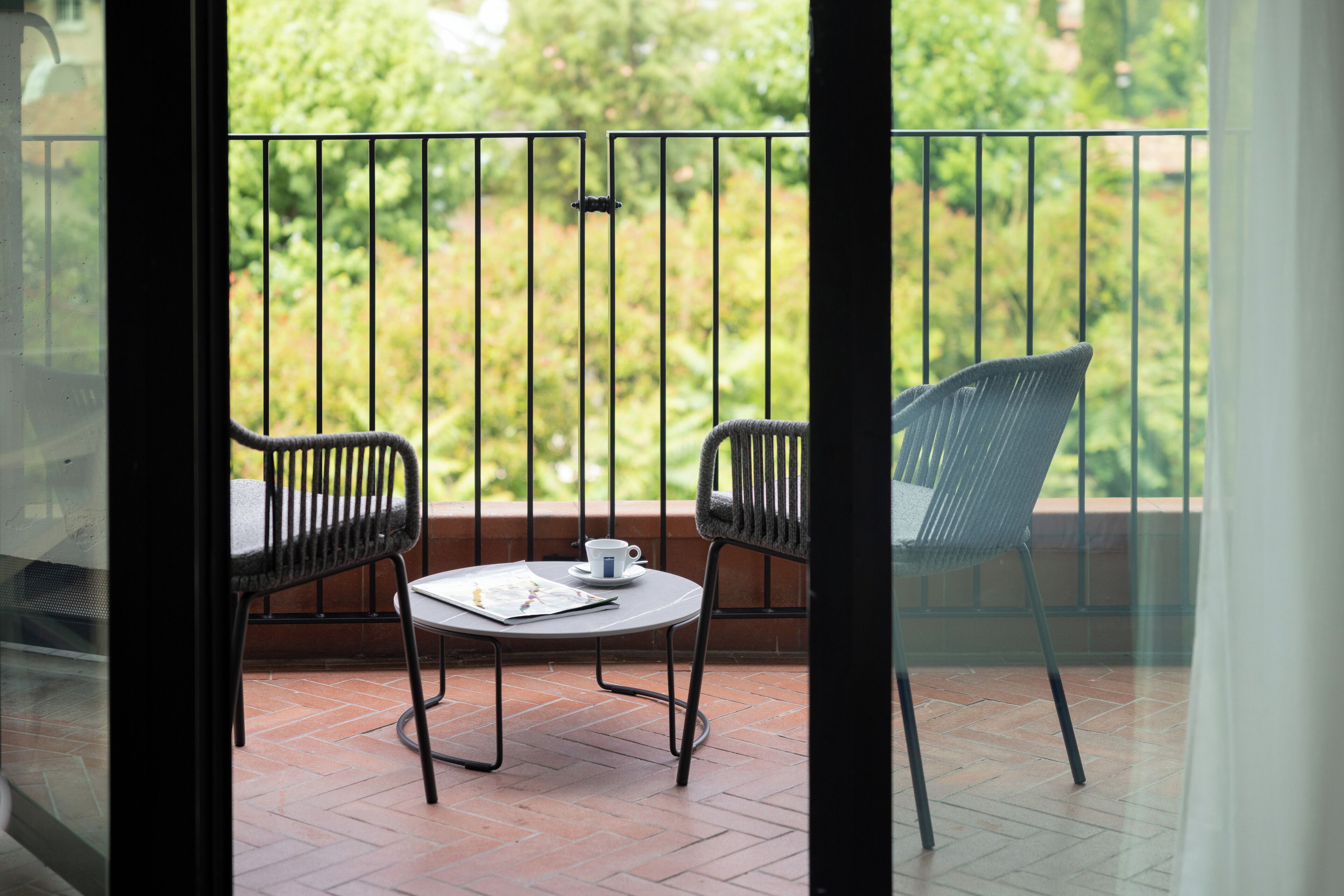 Un balcone con due sedie, un tavolo, una tazza e un giornale.