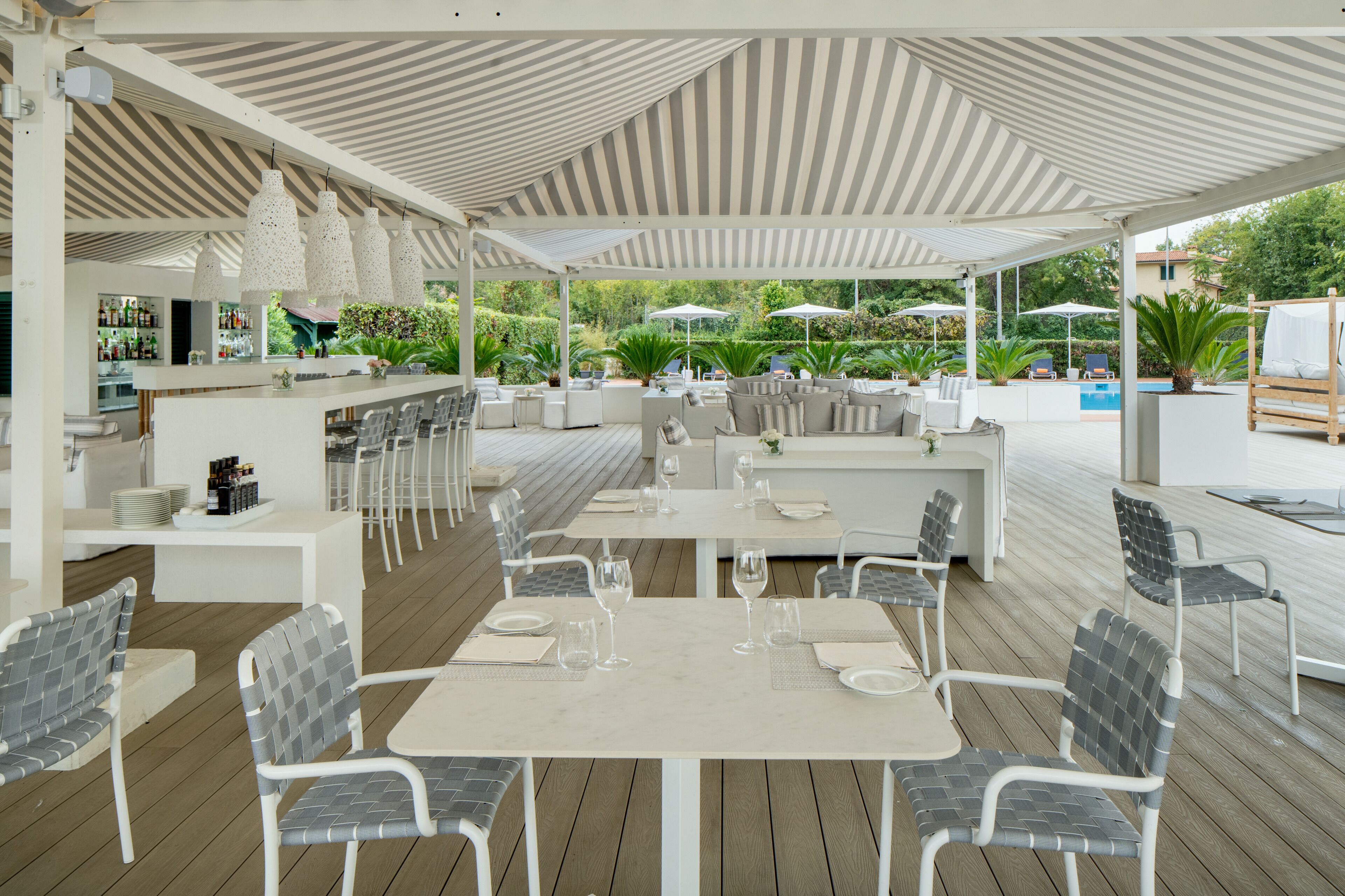 Een terras met tafels, stoelen, een bar en parasols.
