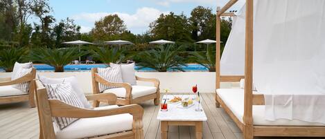 Una terraza de madera con mobiliario exterior y una piscina.