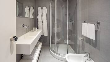 Une salle de bain moderne avec une douche à parois de verre, un lavabo blanc et un meuble-lavabo avec un miroir.