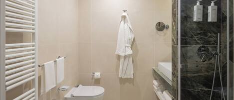 Un baño moderno con inodoro, bidé y zona de ducha con mampara de vidrio.