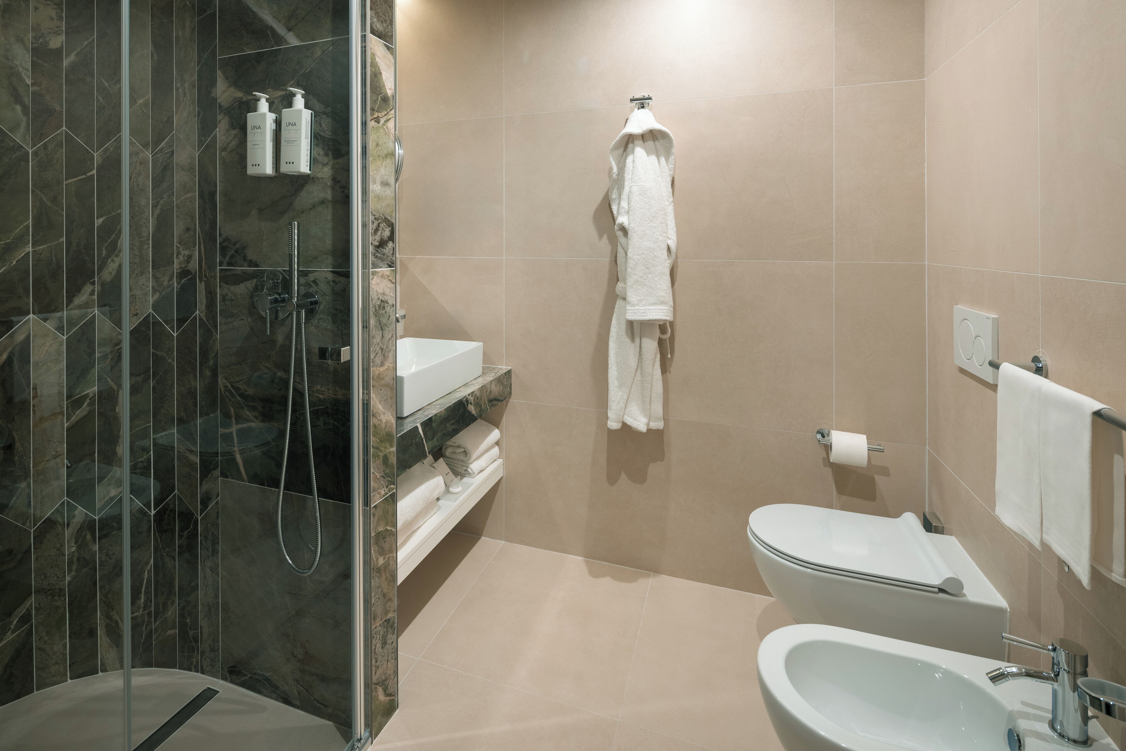 A modern bathroom with a glass-enclosed shower, a white sink, and a toilet.
