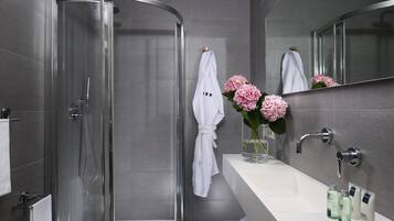 Ein modernes Badezimmer mit einer in Glas eingefassten Dusche, einem weißen Waschbecken und einem Spiegel darüber.