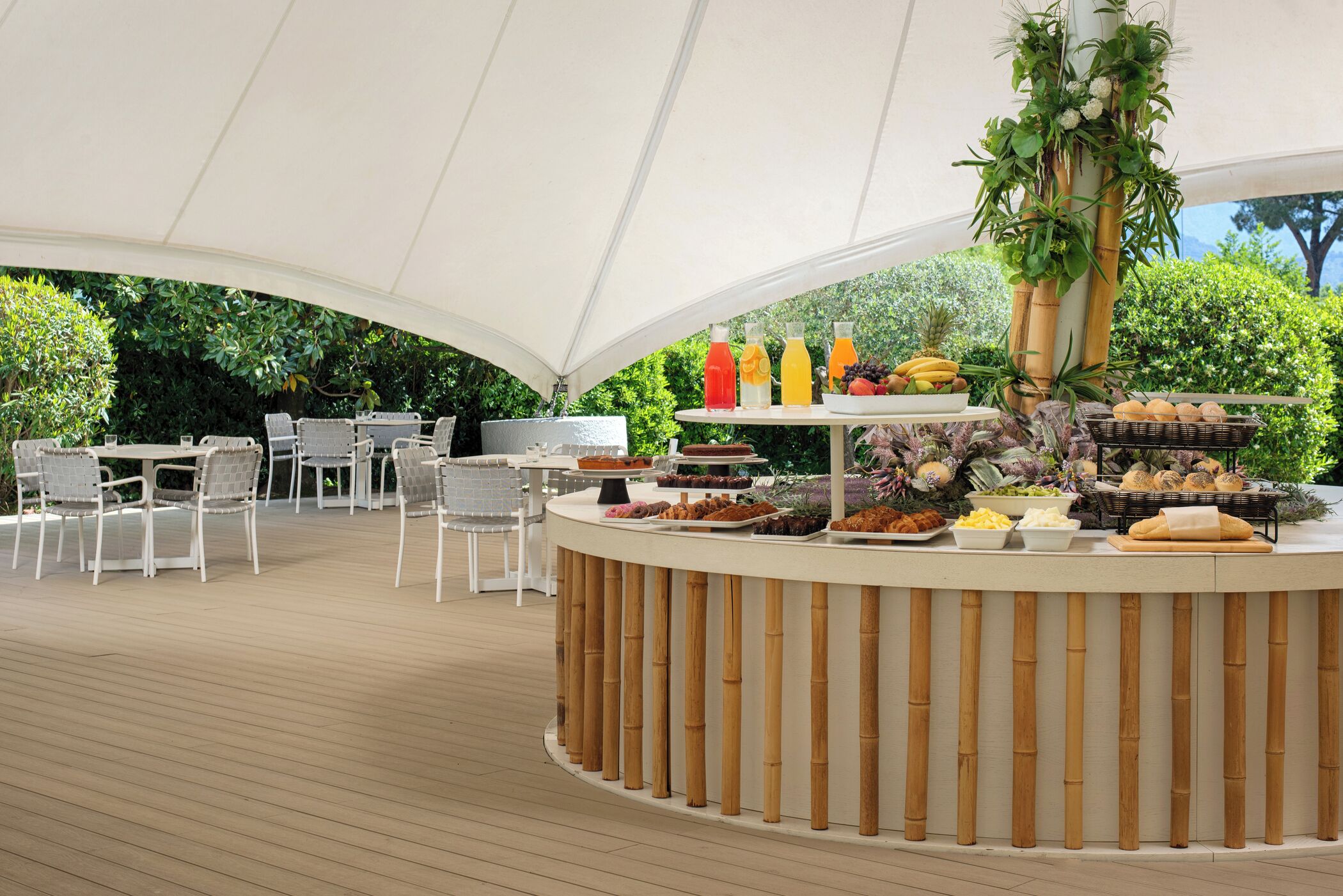A covered outdoor dining area with a buffet table, white chairs, and a wooden deck.
