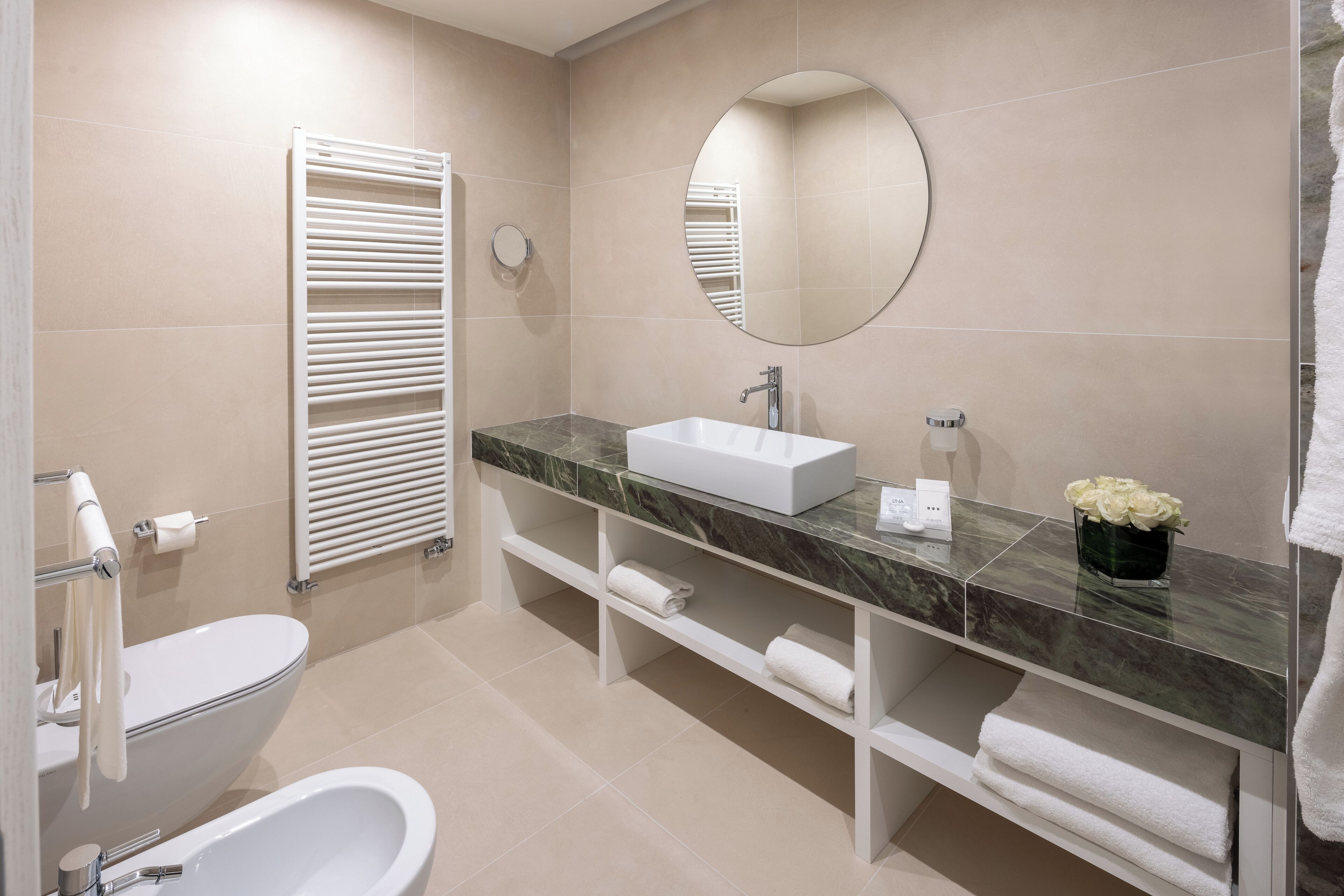 Ein modernes Badezimmer mit Toilette, Waschbecken, Spiegel und Handtuchhalter.