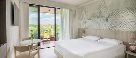 A modern hotel room with a large bed, a dining table, and a view of the outdoors.