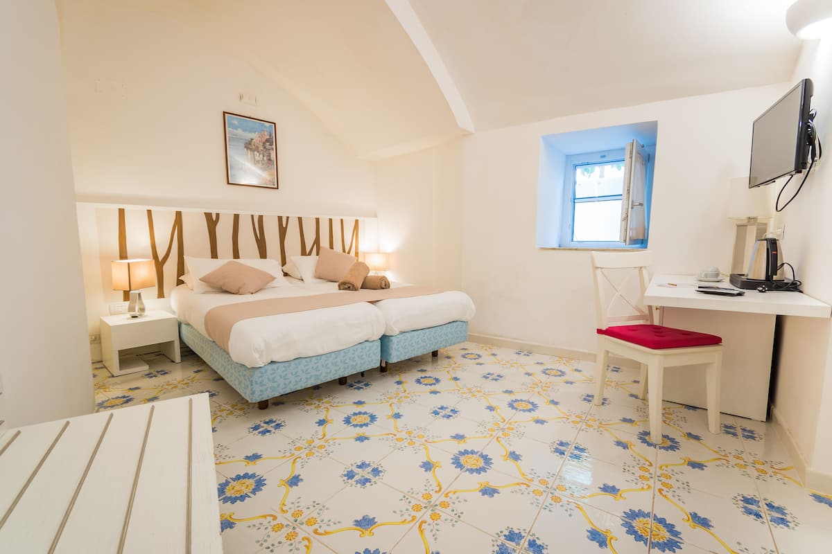 A bedroom with a bed, bedside tables, a desk, and a chair.