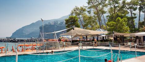 A swimming pool with a view of a mountain and a beach in the background.