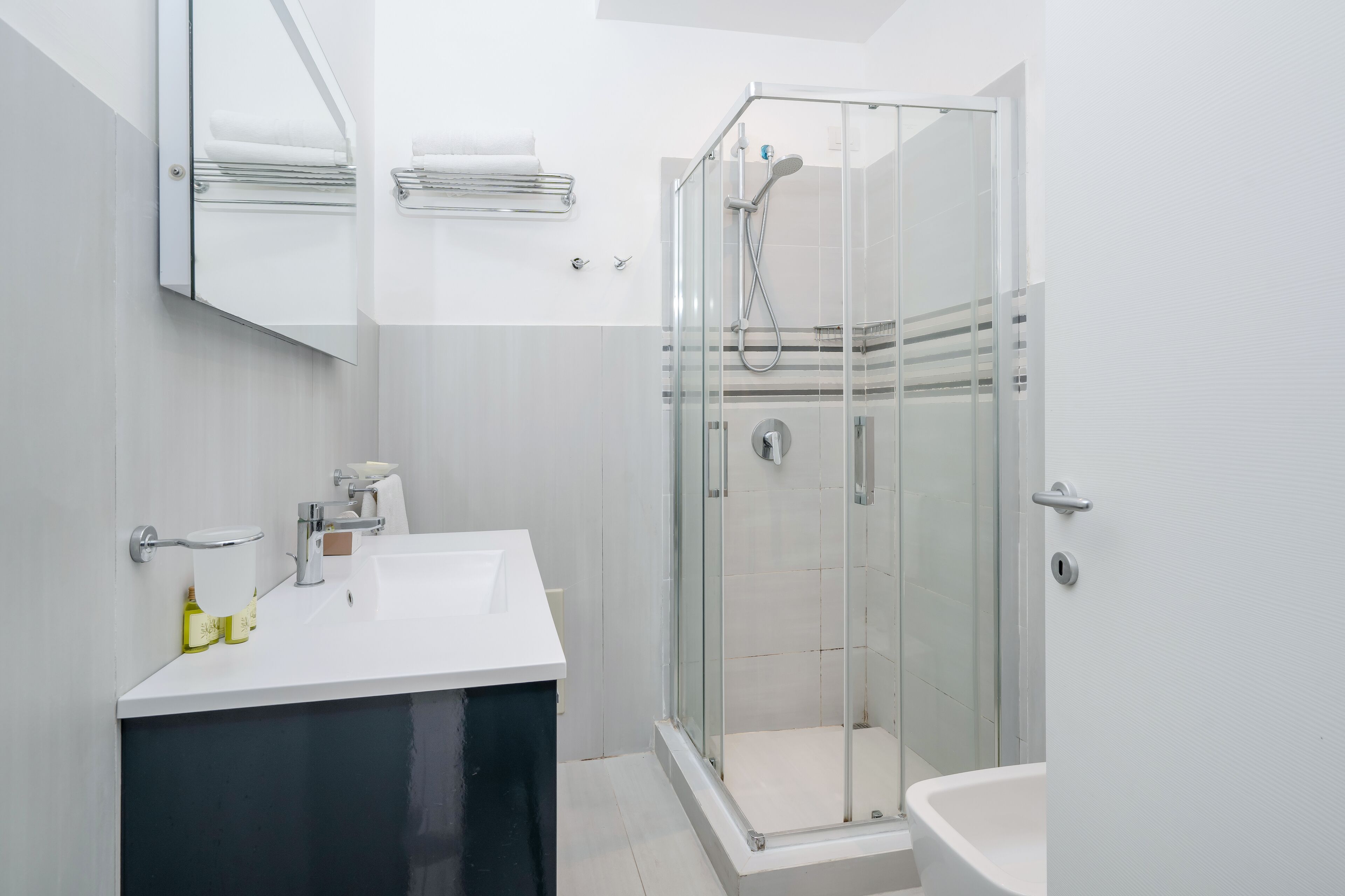 A modern bathroom with a glass-enclosed shower, a white sink, and a dark vanity.
