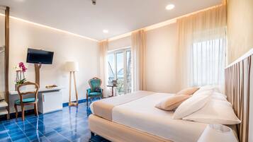 A hotel room with a bed, a desk, a chair, a TV, and a window with curtains.