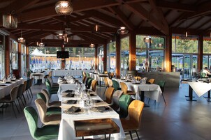 A restaurant with multiple tables set for dining, large windows, and a view of the outdoors.