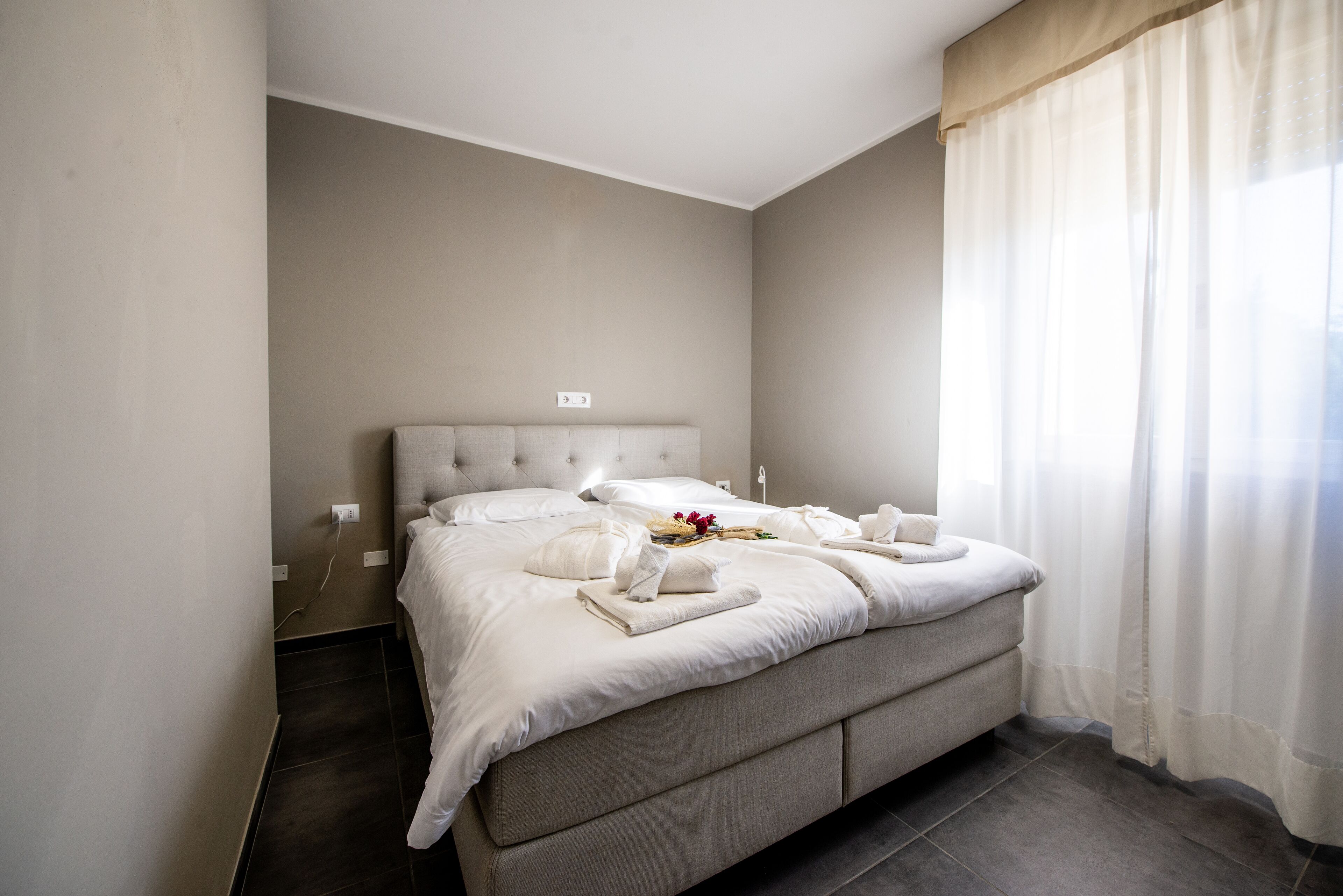 A modern bedroom with a large bed, a bedside table, and a window with curtains.