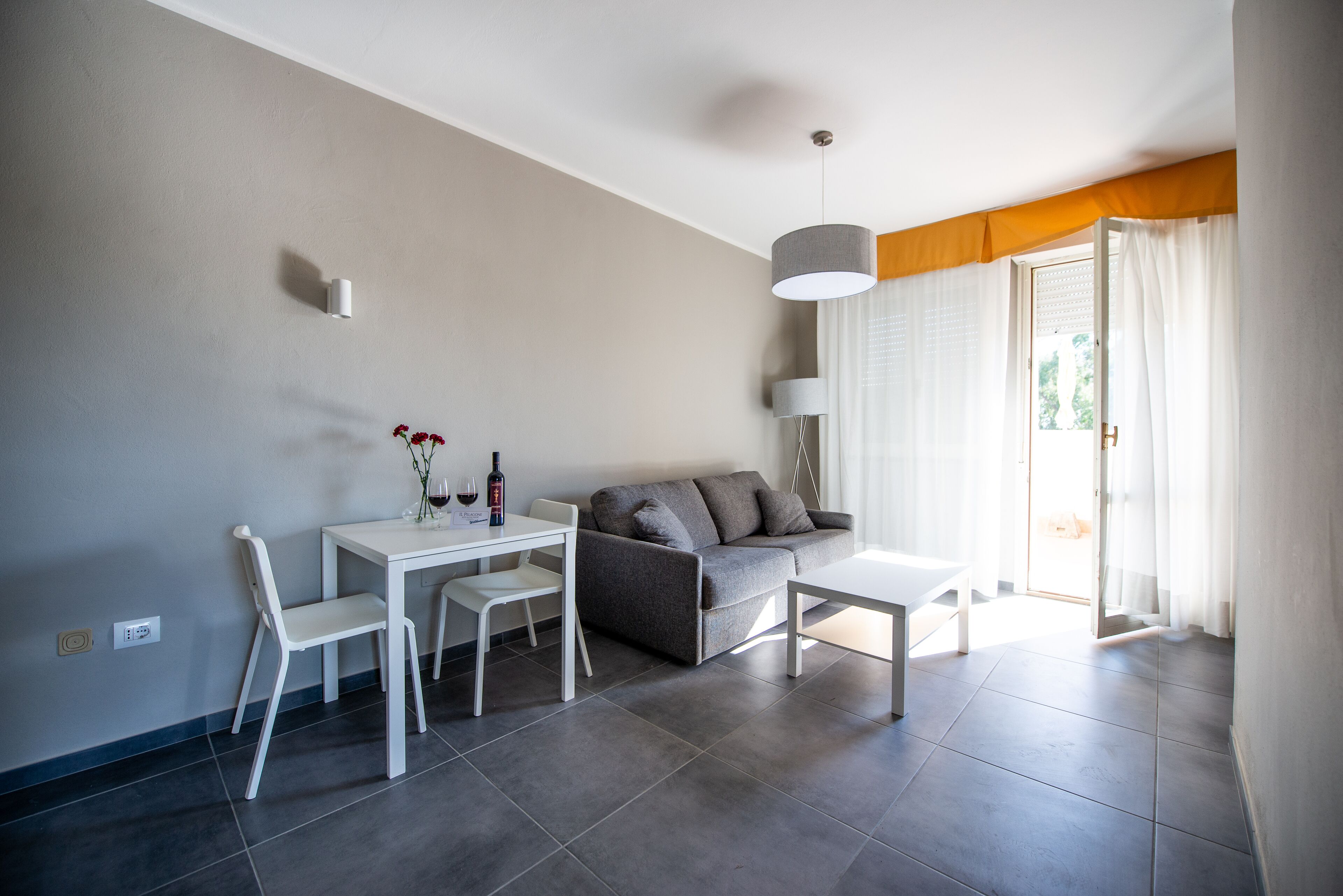 Un salon moderne comprenant un canapé, une table à manger avec des chaises, une table basse et une lampe.