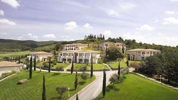 A large, multi-story residential building with multiple balconies, surrounded by well-maintained lawns and trees.