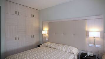 Ein Hotelzimmer mit einem Bett, Nachttischen, einem Telefon und Wandleuchten.