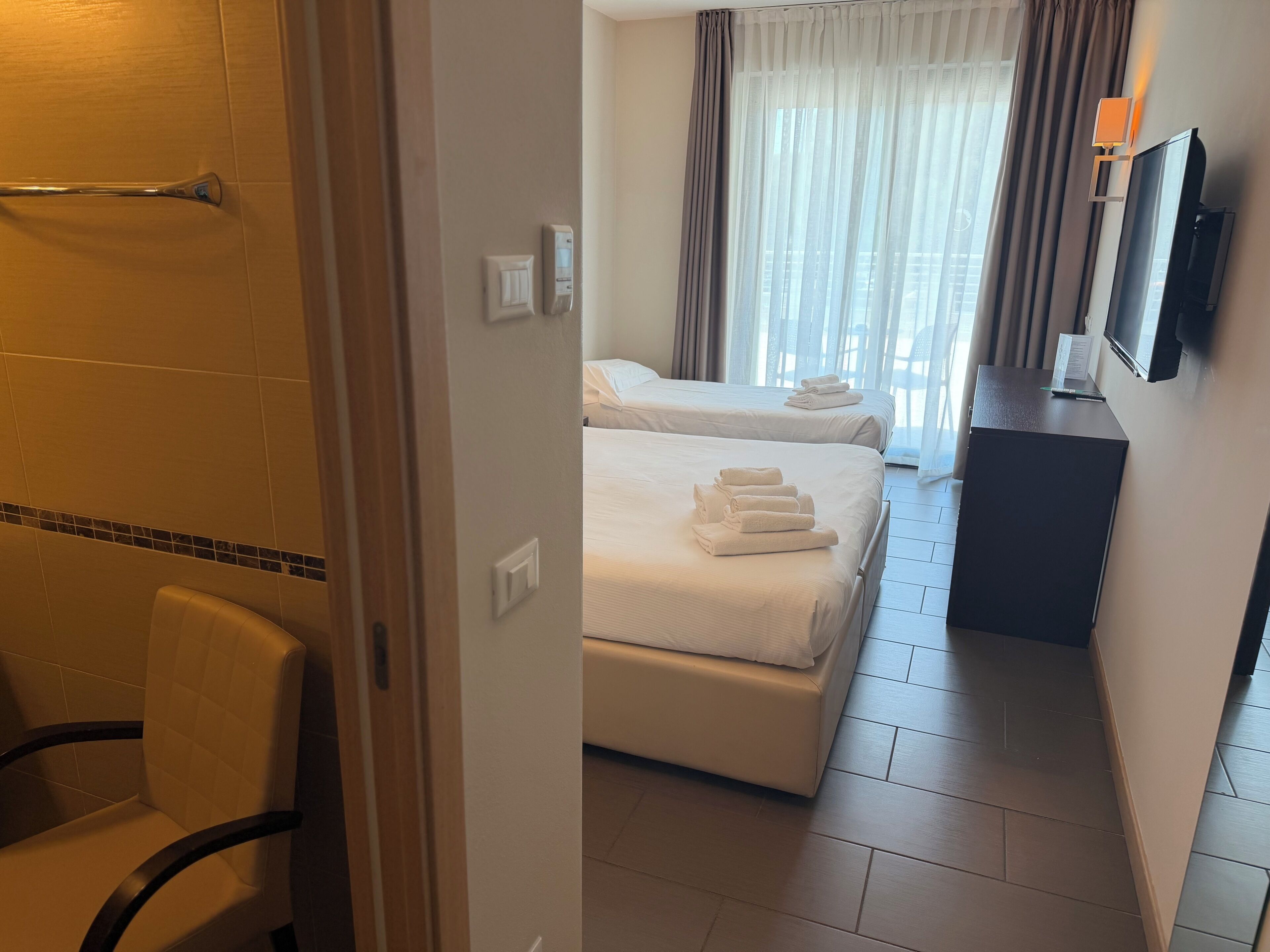 Una habitación de hotel con una cama, un escritorio, una silla y un televisor.