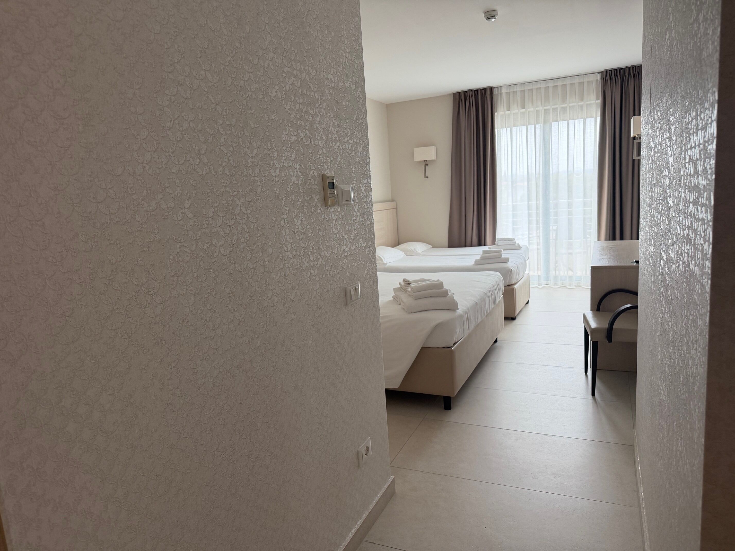 Ein Hotelzimmer mit zwei Betten, einem Schreibtisch und einem Stuhl.