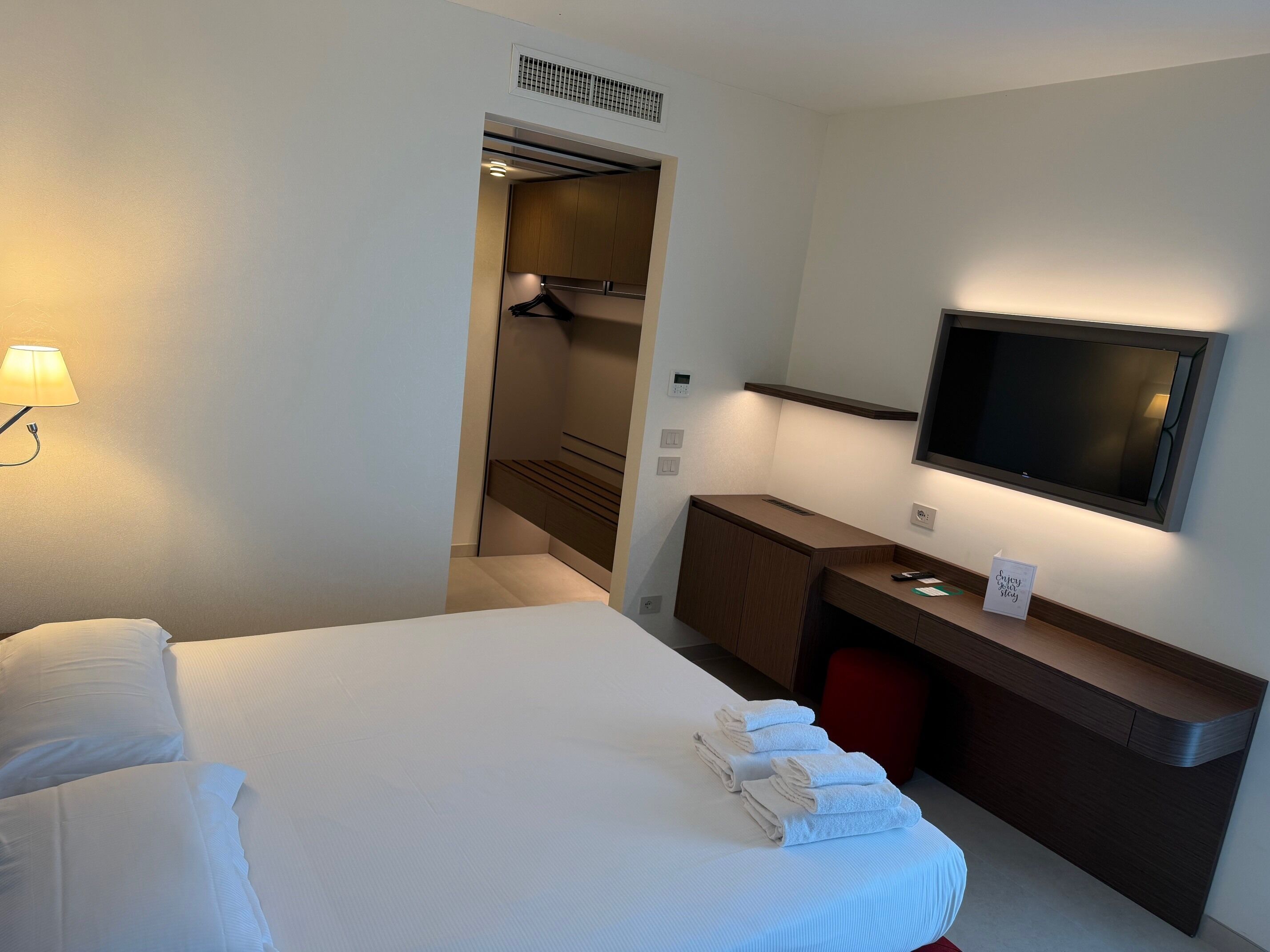 Une chambre d’hôtel équipée d’un lit, d’un bureau, d’une télévision et d’un espace douche.