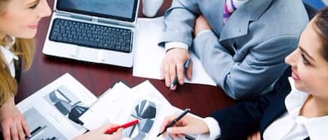 Una reunión de negocios con documentos y una computadora portátil sobre una mesa.