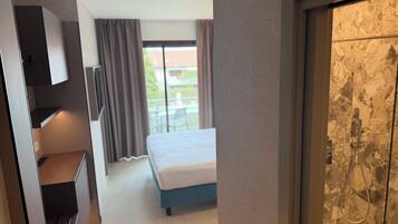 Habitación de hotel con cama, escritorio, armario y vistas al exterior.