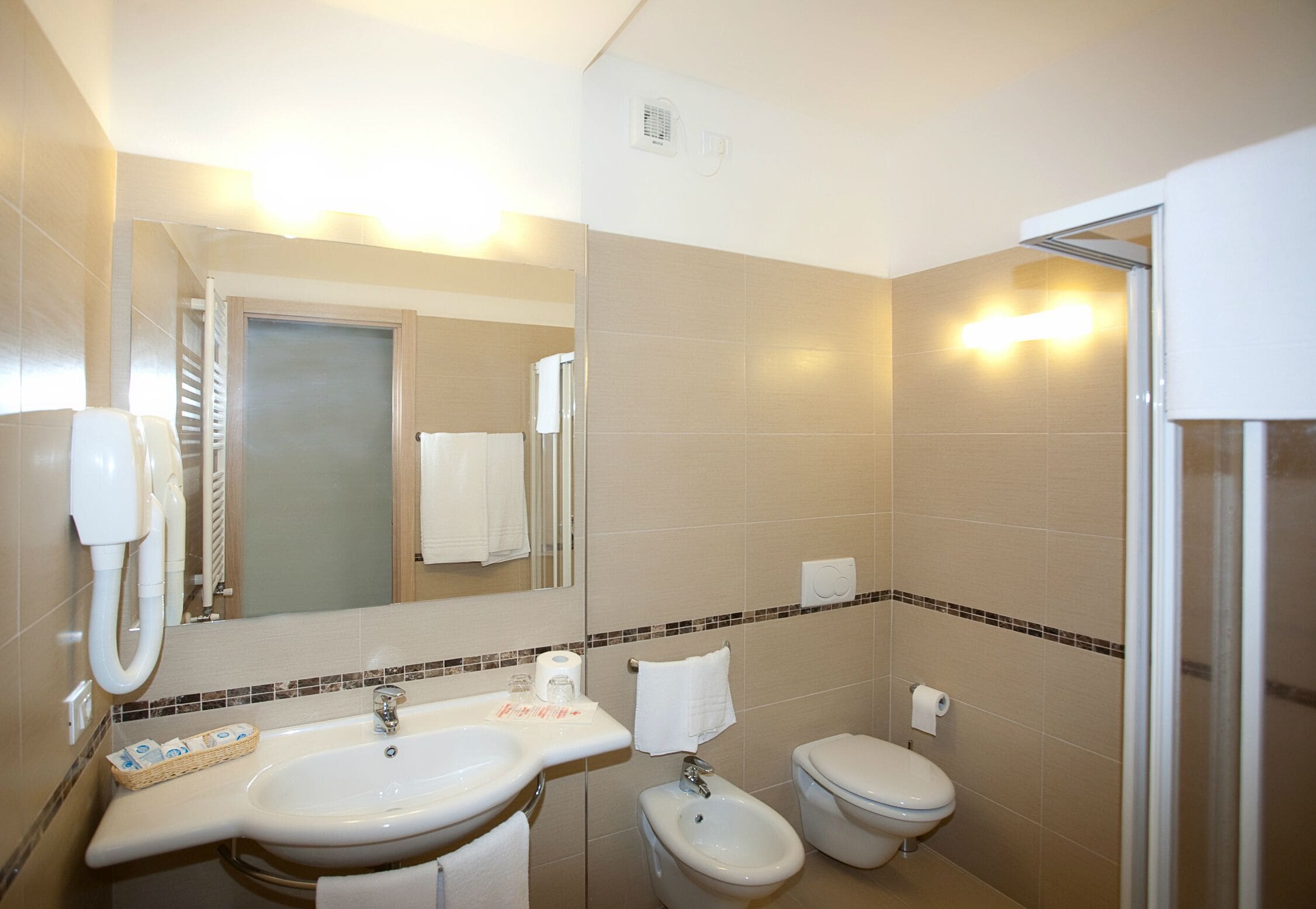 A bathroom with a sink, bidet, toilet, and a mirror.