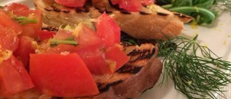 A plate with grilled bread topped with diced tomatoes and herbs.