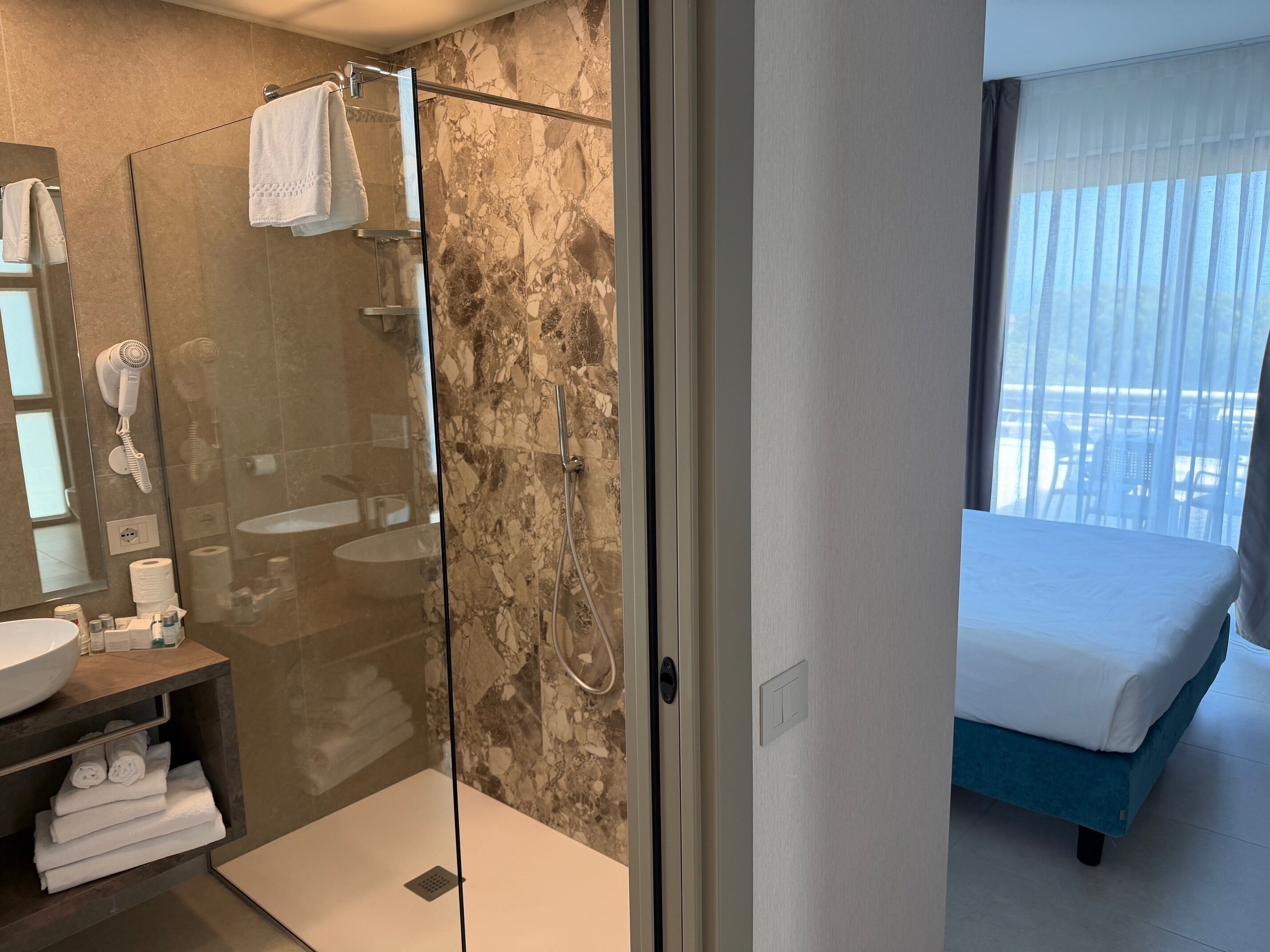 A modern bathroom with a glass-enclosed shower, a sink, and a towel rack.