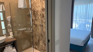 Un baño moderno con ducha de mampara de vidrio, un lavamanos y un perchero para toallas.