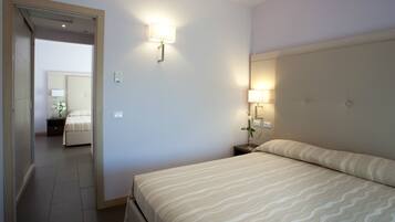 Una habitación de hotel con cama, lámparas de noche, mesita de noche y espejo.
