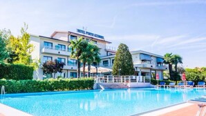 Un hotel con piscina, varios balcones y abundante vegetación.