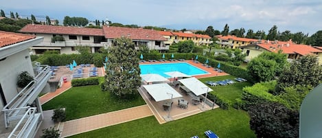 Un patio de hotel con piscina, sillones de descanso y vistas de los edificios circundantes.