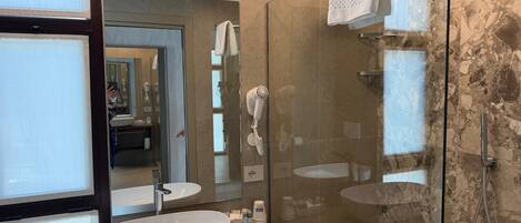 A modern bathroom with a glass-enclosed shower, a large mirror, and a round sink.