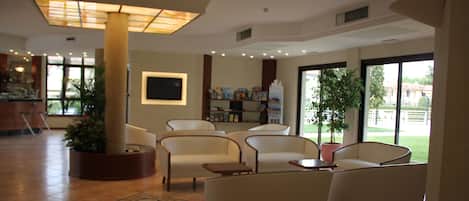 A spacious lobby with comfortable seating, a large window offering a view of the outdoors, and a well-lit ceiling.
